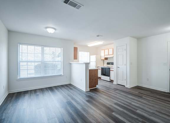 A spacious living room with a kitchenette in the background.