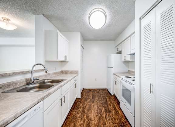 A kitchen with white cabinets and a wooden floor.