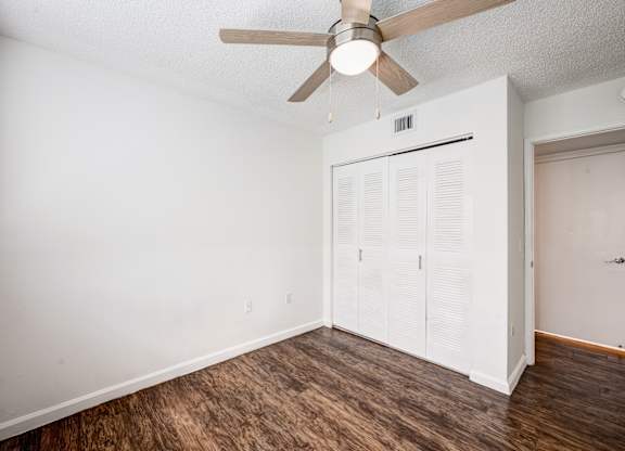 A room with a ceiling fan and a white closet.