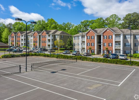 an empty tennis court with apartments in the background at Magnolia Lake Apartments, Georgia