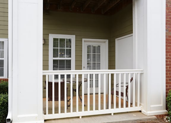 the front porch of a home with a white railing and a porch swing at Magnolia Lake Apartments, Carrollton, 30117