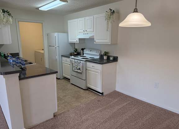 A kitchen with white cabinets and a black countertop.