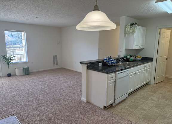 A kitchen with white cabinets and a black countertop.