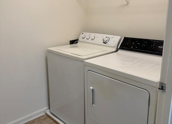 A white wall with a white door and a white cabinet with a black handle.