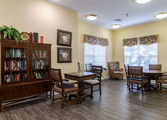 A room with a wooden floor, a bookcase, a table with chairs, and pictures on the wall.at The Gardens of Stafford, 22193  