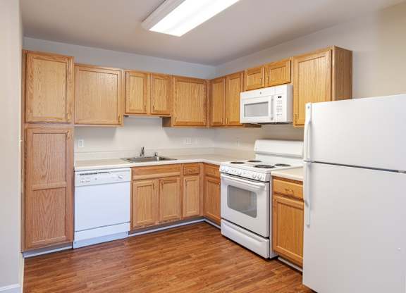 A kitchen with wooden cabinets and white appliances.at The Gardens of Stafford, Stafford, VA  