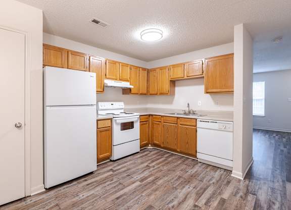 A kitchen with wooden cabinets and white appliances.at The Village at England Run, Fredericksburg, Virginia  