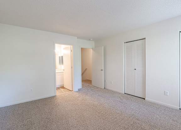 A sparsely furnished room with a carpeted floor and white walls.at The Village at England Run, Fredericksburg 