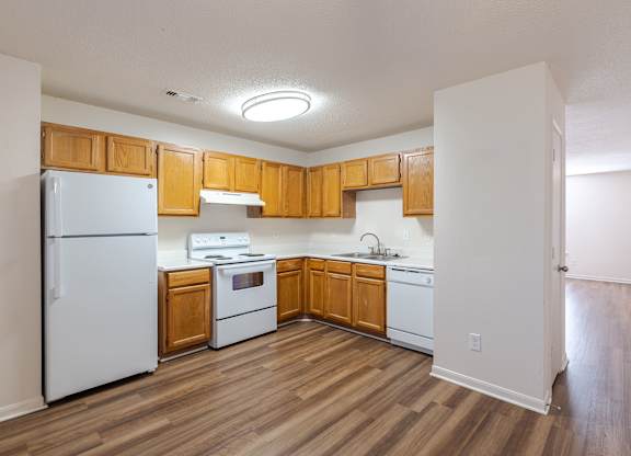 A kitchen with wooden cabinets and white appliances.at The Village at England Run, Fredericksburg, VA  