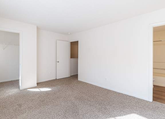 A white room with a carpeted floor and a door.at The Village at England Run, Fredericksburg, VA 22406  