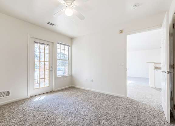 an empty living room with white walls and a ceiling fan