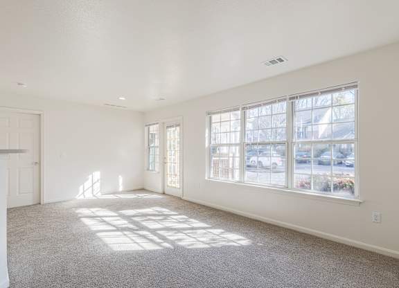 the living room of a home with a large window and carpet