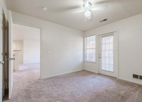 an empty living room with white walls and a ceiling fan