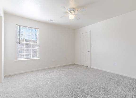 an empty bedroom with white walls and a ceiling fan
