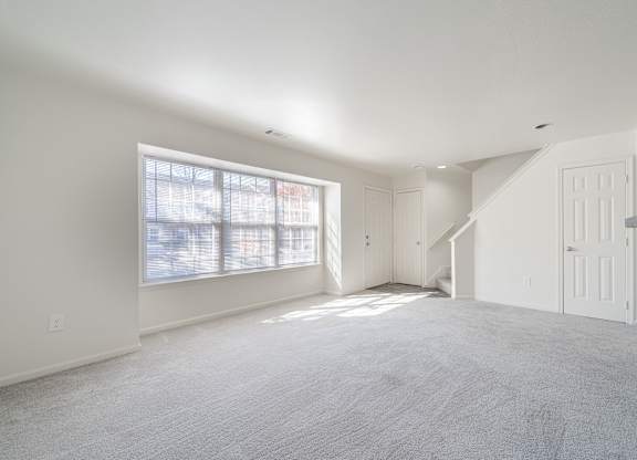 an empty living room with white walls and a large window