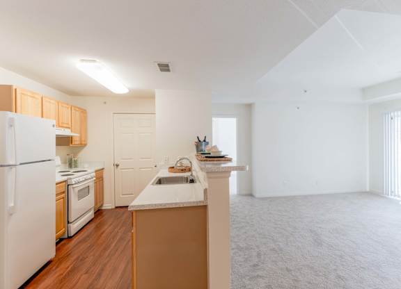 A kitchen with white appliances and wooden cabinets.at Woodwind Villa Apartments, Woodbridge, VA