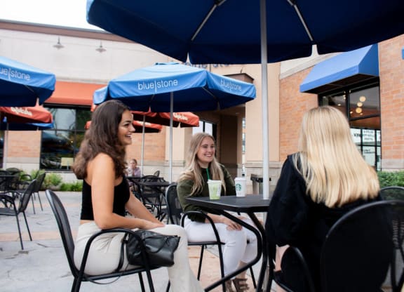 three women sitting at a table under an umbrella at Bluestone Lofts, Minnesota, 55803
