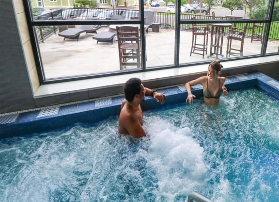 a man and a woman in a jacuzzi in front of a windowat Bluestone Lofts, Duluth