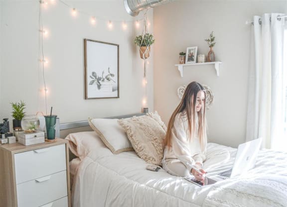 a woman sitting on a bed with a laptop computer at Bluestone Lofts, Duluth, MN