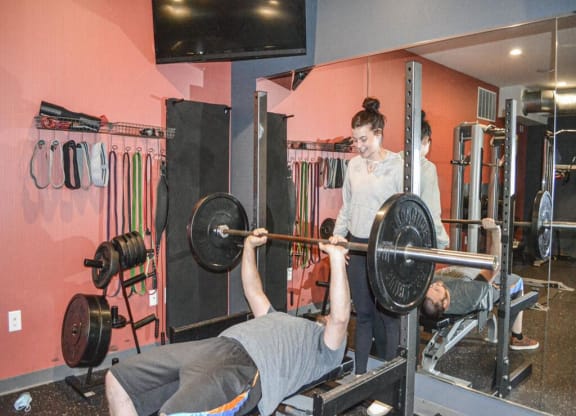 a man lifting a barbell in a gym with a woman standing behind himat Bluestone Lofts, Minnesota, 55803