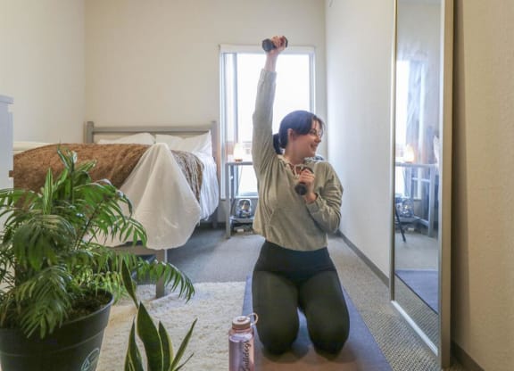 a woman sitting on the floor with her arms up in a roomat Bluestone Lofts, Duluth