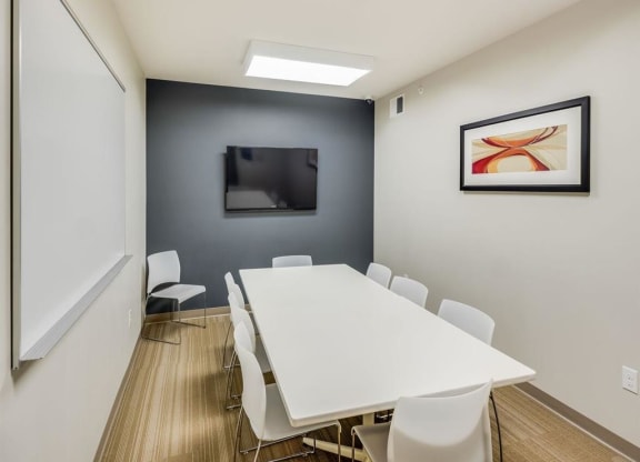 a conference room with a white table and chairs and a television at Bluestone Lofts, Minnesota