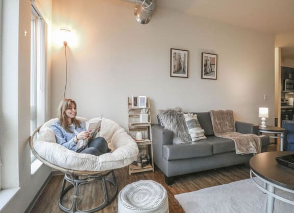 a woman sitting in a chair reading a book in a living room at Bluestone Lofts, Duluth, 55803