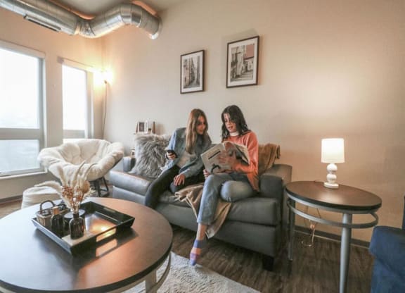 two women sitting on a couch in a living room reading a magazine at Bluestone Lofts, Duluth