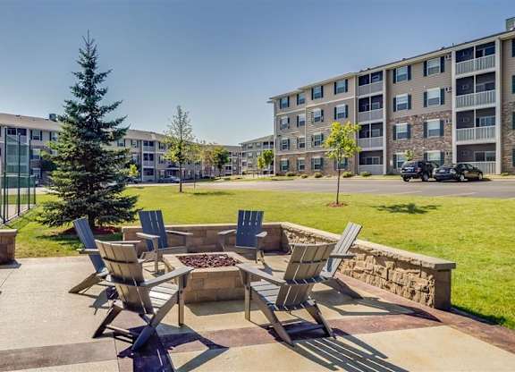 a patio with chairs and a fire pit in front of an apartment building  at Boulder Ridge, Duluth, MN 55811