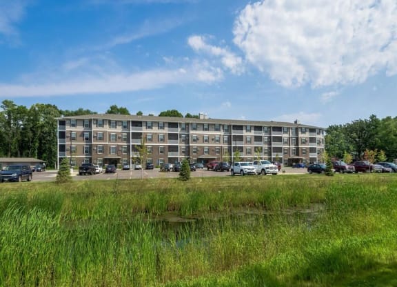 a large apartment building with cars parked in front of it at Arbor Ridge, Forest Lake, MN, 55025