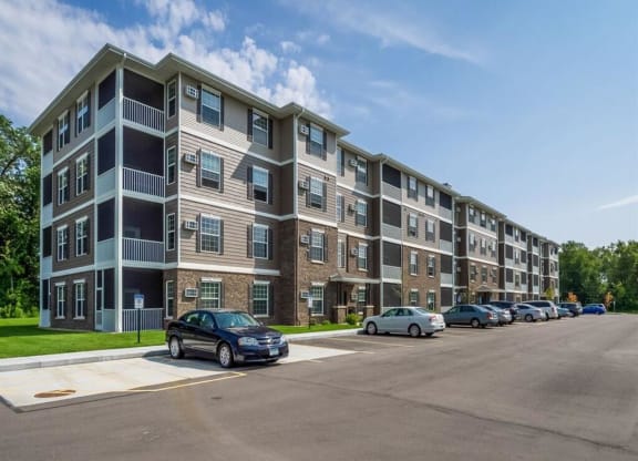 an apartment building with cars parked in a parking lot at Arbor Ridge, Forest Lake