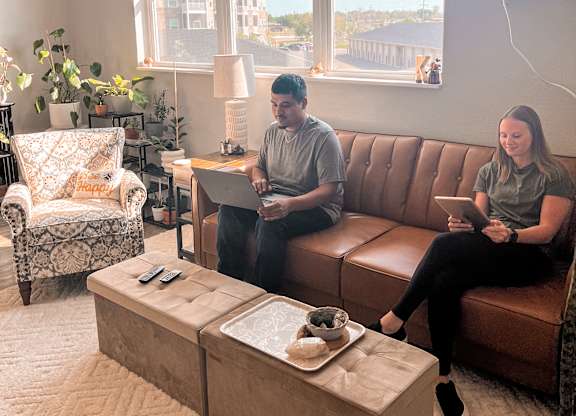 Two people sitting on a couch in a living room with a coffee table in front of them.