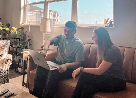 Two people sitting on a couch with a laptop.