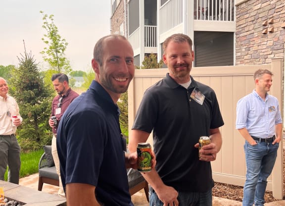 two men standing in front of a house holding beers  at Timber Ridge, Minnesota