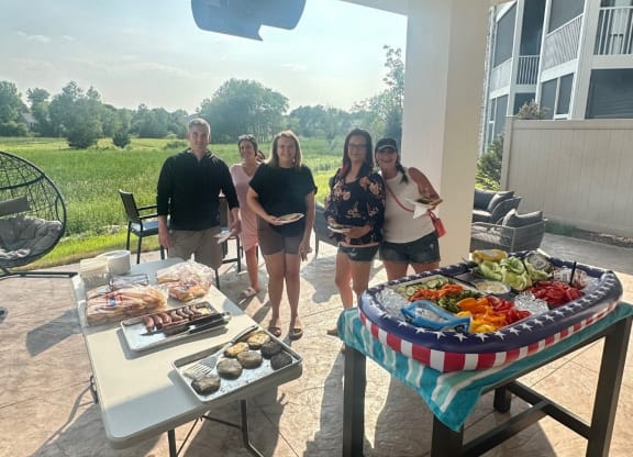 a group of people standing around a table with food on it  at Timber Ridge, Forest Lake, MN, 55025