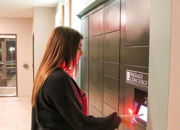 a woman is pressing a button on a door of a parcel receiving system  at Timber Ridge, Forest Lake
