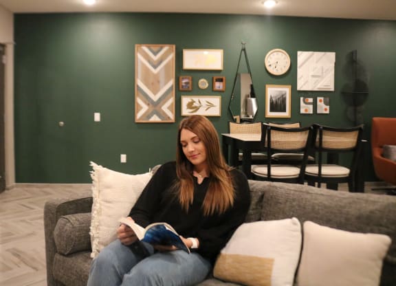 a woman sitting on a couch reading a book in a living room  at Timber Ridge, Forest Lake, MN