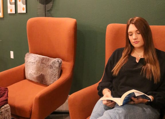 a woman sitting in a chair reading a book  at Timber Ridge, Forest Lake, MN, 55025