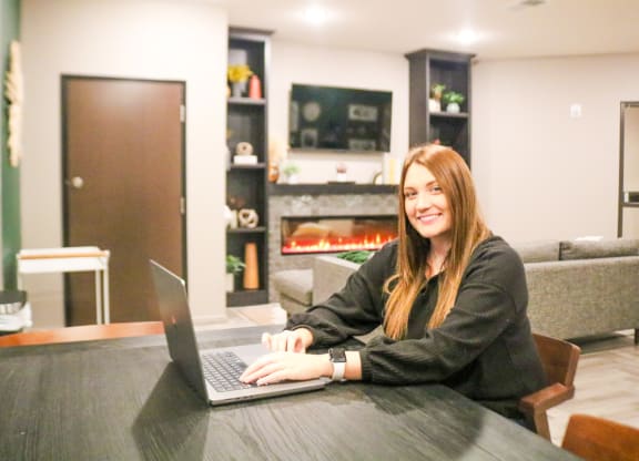 a woman sitting at a table with a laptop computer  at Timber Ridge, Forest Lake, MN, 55025