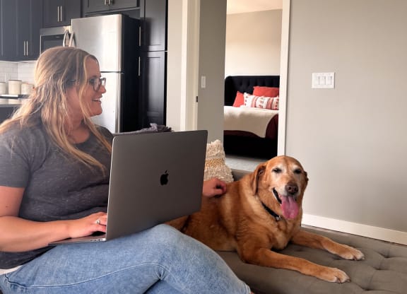 a woman sitting on a couch with a laptop computer on her lap and a dog  at Timber Ridge, Minnesota, 55025