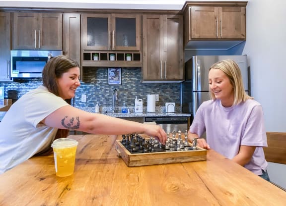 two women playing chess at a table in a kitchen  at Timber Ridge, Forest Lake