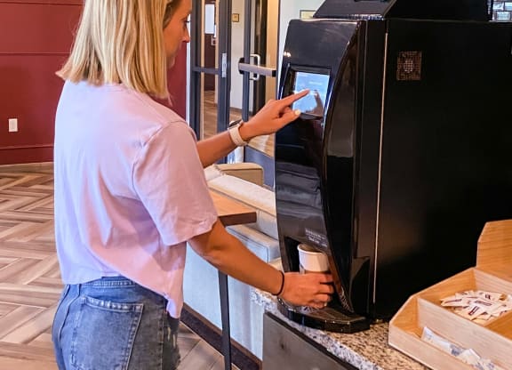 a woman putting a cup into an automatic coffee machine  at Timber Ridge, Forest Lake