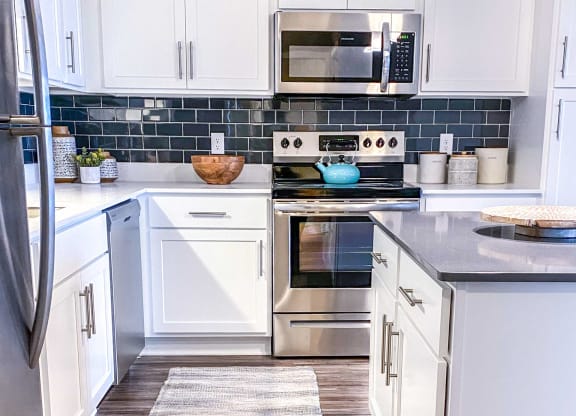 a kitchen with white cabinets and stainless steel appliances and a rug on the floor  at Timber Ridge, Minnesota, 55025