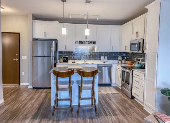 a kitchen with stainless steel appliances and two bar stools  at Timber Ridge, Forest Lake, 55025