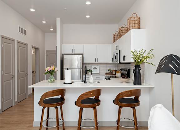 A kitchen with a white countertop and wooden bar stools.at Converge KC Uptown, Kansas City, MO 64111