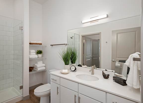 A white bathroom with a toilet, sink, and mirror.at Converge KC Uptown, Kansas City Missouri