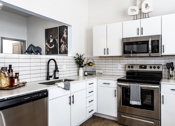 A modern kitchen with white cabinets and a black stove top.at Converge KC Uptown, Kansas City, 64111