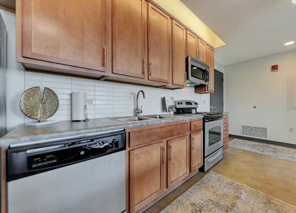 the kitchen is equipped with stainless steel appliances and wood cabinets at Parkhaus Apartments, Lincoln, NE