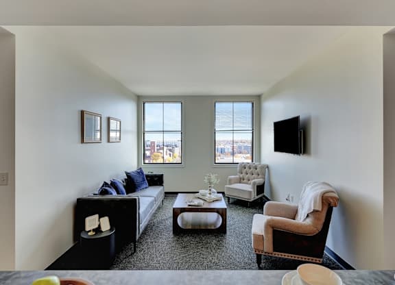 a living room with a couch and two chairs and a tv at Parkhaus Apartments, Lincoln, NE 68508