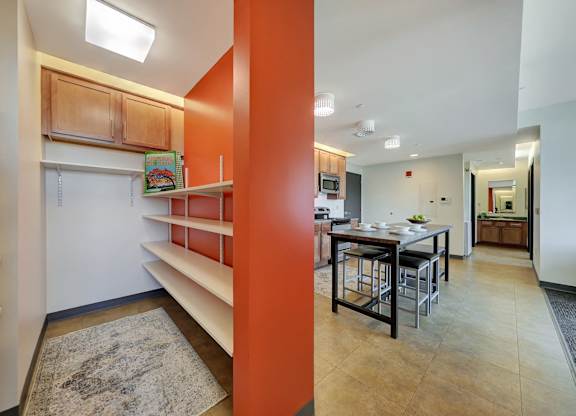 a dining room and kitchen with a table and chairs and a wall with shelves at Parkhaus Apartments,Nebraska 68508